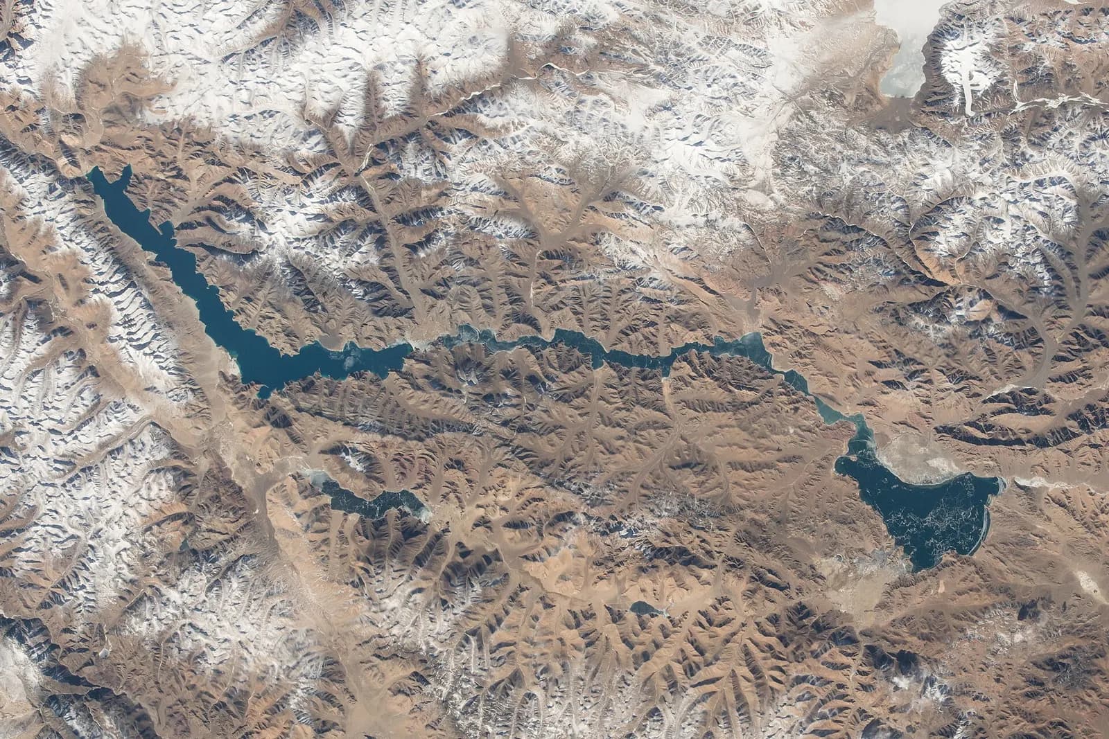 Turquoise water of Pangong Tso with barren brown mountains and blue sky in Ladakh